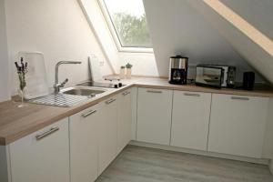 cocina con armarios blancos, fregadero y ventana en Zuhause Woanders - Kuhtrade, en Wildeshausen
