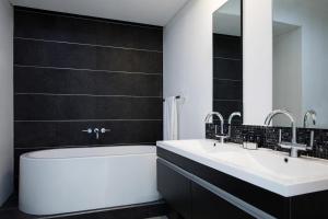 a bathroom with two sinks and a tub and a mirror at The Capital 20 West in Johannesburg