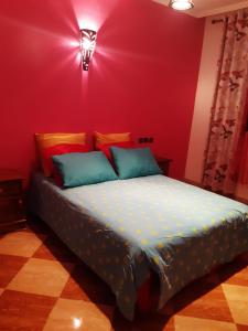 ein Schlafzimmer mit einem Bett mit einer roten Wand in der Unterkunft Villa Fatima in Meknès
