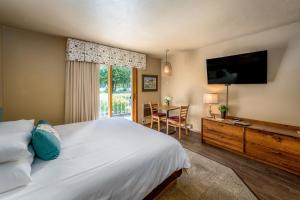 Schlafzimmer mit einem Bett, einem Schreibtisch und einem TV in der Unterkunft Somerset Inn & Suites in Ephraim