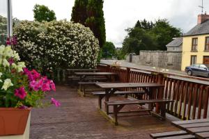 a row of benches on a wooden deck with flowers at Fairhill House Hotel in Clonbur