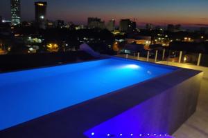 a blue swimming pool on the roof of a building at night at Delfines Collection Hotel by Mercure in Santa Cruz de la Sierra