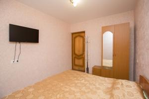 a bedroom with a bed and a television on the wall at Guesthouse na ulitze Mimoz 9 in Adler