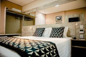 Un dormitorio con una cama grande con almohadas. en Bristol Viçosa Hotel, en Viçosa