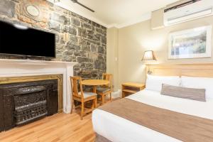 una camera d'albergo con letto e camino di Hotel Jardin du Gouverneur a Québec