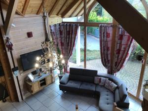 a living room with a couch and a tv at Le Chalet du Pont des Fées - Sauna & SPA in Gérardmer