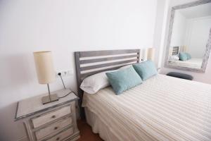 1 dormitorio con 1 cama con lámpara y espejo en Apartamento Rialto, en Málaga