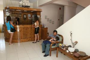 un hombre sentado en una silla con un bebé en una habitación en Guest House Polyvotis en Mandrakion