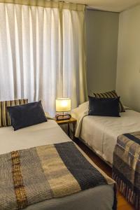 2 camas en una habitación con ventana en Alessandria Apart - El Bosque Norte, en Santiago