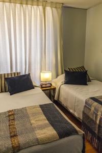 two beds in a room with a window at Alessandria Apart - El Bosque Norte in Santiago