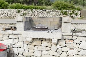 eine Steinmauer mit einem Kamin vor einer Straße in der Unterkunft Apartments MAK in Račišće