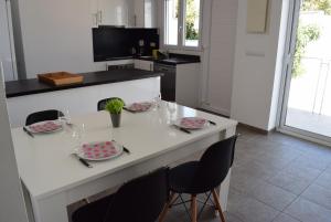 a white kitchen with a table with plates and chairs at casa con piscina privada y cerca playa ref 382 in Empuriabrava