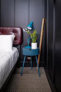 a blue table with a plant on it next to a bed at The Chicago Hotel Collection River North in Chicago