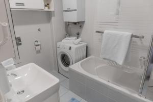 a white bathroom with a washing machine and a sink at Alpha apartment in Zagreb