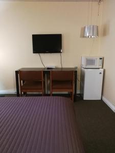 a room with a desk with a tv and a microwave at Star Motel in Morden