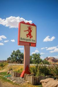 a sign for a koko spell inn in a field at Kokopelli Inn in Bluff