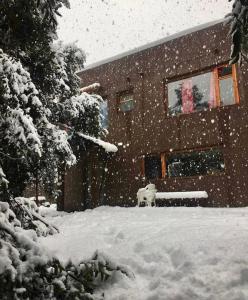 uma casa coberta de neve na frente em Ciao Bariloche - habitaciones privadas en hostel em San Carlos de Bariloche