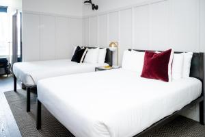 two beds in a hotel room with white and red pillows at The Chicago Hotel Collection River North in Chicago