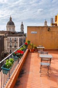 un balcón con mesas y flores en un edificio en Terrazza Santa Chiara, en Catania