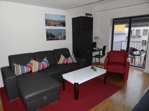 a living room with a black couch and a red chair at Backbord Und Steuerbord in Stralsund
