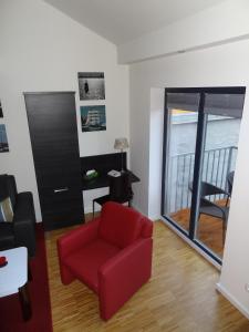 ein Wohnzimmer mit einem roten Stuhl und einem Balkon in der Unterkunft Backbord Und Steuerbord in Stralsund