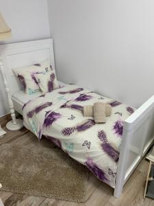 uma cama com um edredão e almofadas roxos e brancos em Smiley Rezident em Sibiu