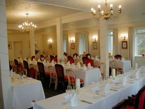 a banquet room with white tables and red chairs at Gairloch Highland Lodge in Gairloch