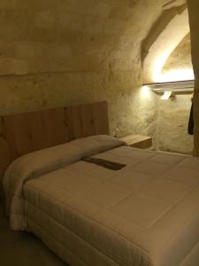 een slaapkamer met een groot bed in een stenen kamer bij Porticina Verde Suite in Matera
