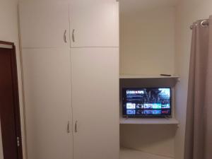 a room with white cabinets and a tv in it at Loft Pinheiros in Blumenau