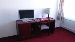 una scrivania con monitor e sedia in una stanza di Hotel Restaurant Margaretenhof a Überherrn