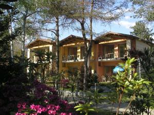 dom z drzewami i kwiatami przed nim w obiekcie Villaggio Turistico Riviera w mieście Cannobio
