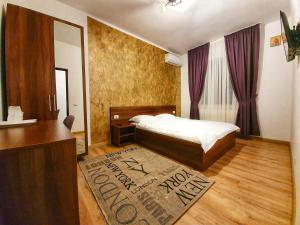 a bedroom with a bed and a dresser and a mirror at Vily Luxury Rooms in Focşani
