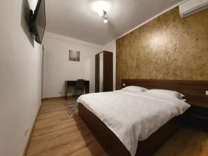 1 dormitorio con 1 cama y TV en la pared en Vily Luxury Rooms, en Focşani