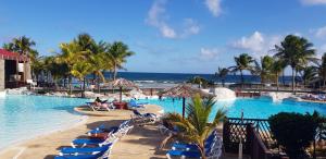 a resort swimming pool with lounge chairs and the ocean at Caribbean sea view in Saint-François