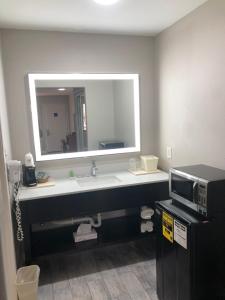 a bathroom with a sink and a mirror and a microwave at Diboll Inn and Suites in Diboll