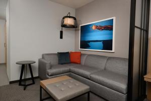 Hyatt Place Pena Station/Denver Airport في دنفر: غرفة معيشة مع أريكة رمادية وطاولة