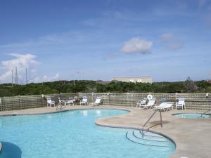 a swimming pool with white chairs and a table and chairs at Cape Hatteras Motel in Buxton