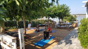 grupa ludzi uprawiających jogę na pokładzie w obiekcie Apartments Villa Papalina 2 w Rabie