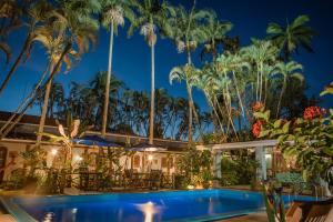 a resort with a pool and palm trees at night at Plaza Inn Pousada do Capitão in Ilhabela