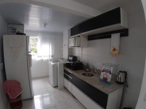 una pequeña cocina con fregadero y nevera. en AP de Praia Mar Azul - Praia da Vila, en Imbituba