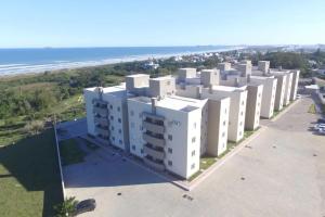 una vista aérea de un gran edificio blanco con el océano en AP de Praia Mar Azul - Praia da Vila, en Imbituba
