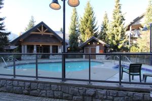 a swimming pool with a fence and a house at Glacier's Reach by Whistler Retreats in Whistler