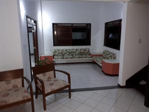sala de estar con 2 sillas y sofá en Guarajuba - casa em condomínio corais a 200 metros da praia, en Camaçari