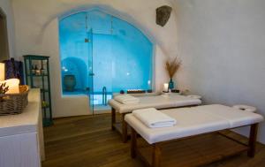 a room with three beds and a blue window at Iconic Santorini, a Boutique Cave Hotel by Sandglass in Imerovigli