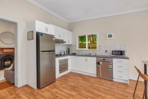 a kitchen with white cabinets and a stainless steel refrigerator at The Barton - Easy Tram to City in Thebarton
