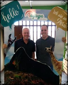 deux hommes debout devant un panneau avec une girafe dans l'établissement Taytaypa Rooms & Apartments Lima Airport, à Lima