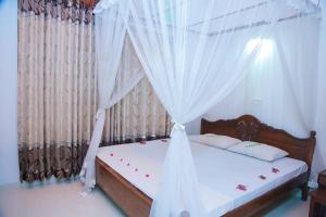 a bedroom with a bed with white curtains at Ananda Villa Bentota in Bentota