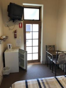 a room with a television and a refrigerator and a table at Truro weighbridge motel in Stockwell