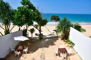 a beach with tables and chairs and the ocean at Garland Beach Villa in Ambalangoda