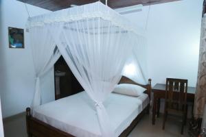 a bedroom with a bed with white mosquito netting at Ananda Villa Bentota in Bentota